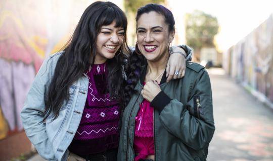 latino women smiling and laughing in mural alley