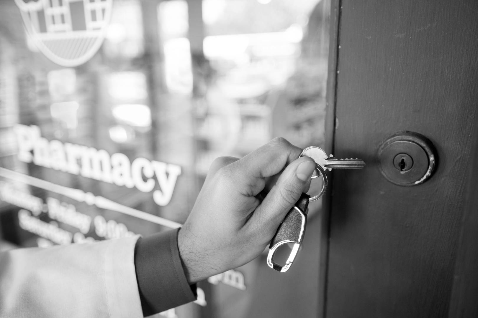 A pharmacist opens the door to his pharmacy