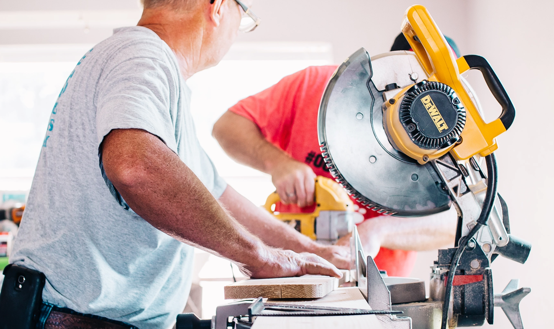 Two men sawing and drilling wood in a pharmacy under construction