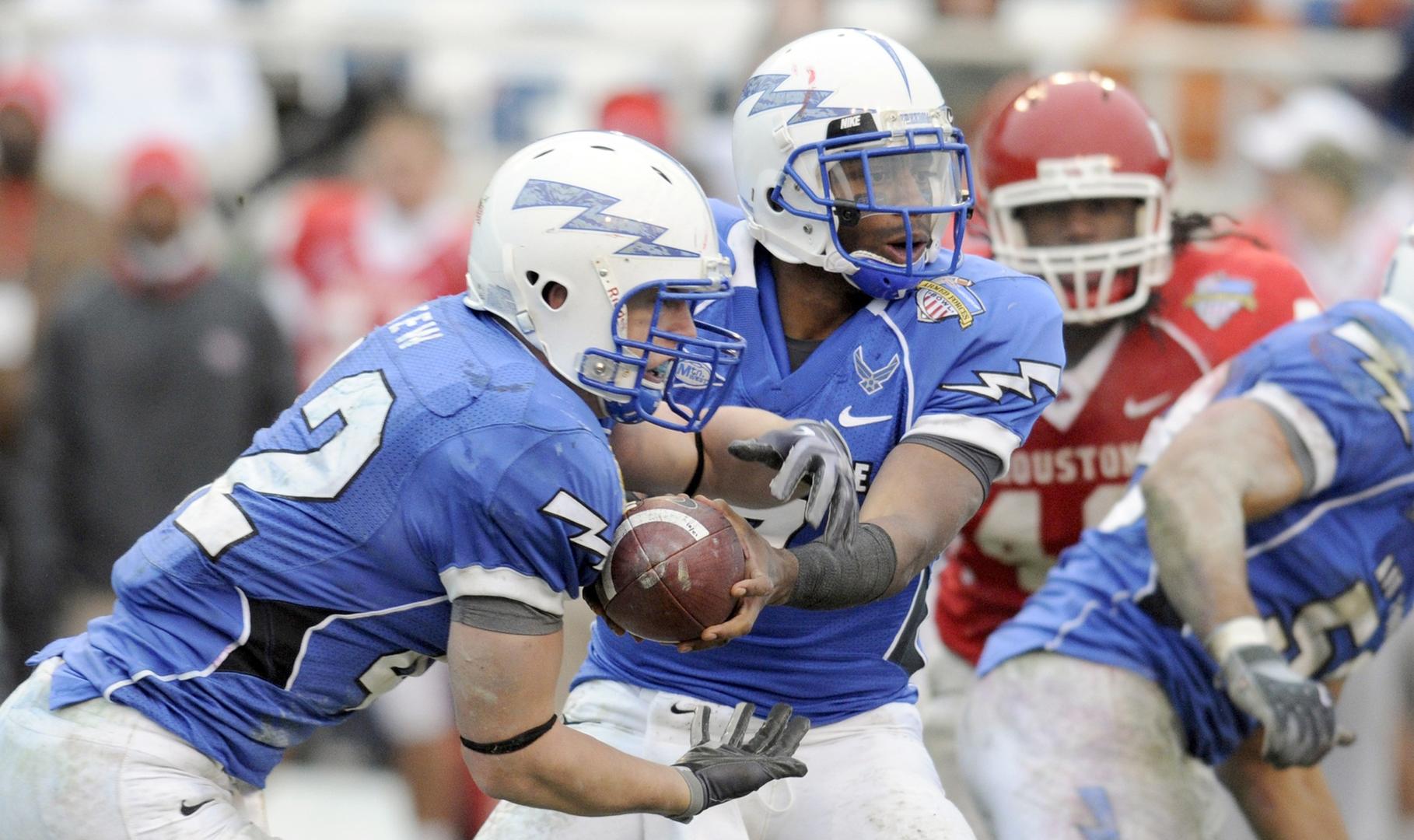 A quarterback handing off a football to a running back