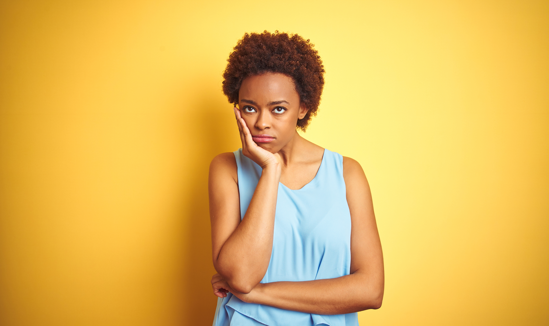 A woman holding her chin in her hand and looking annoyed