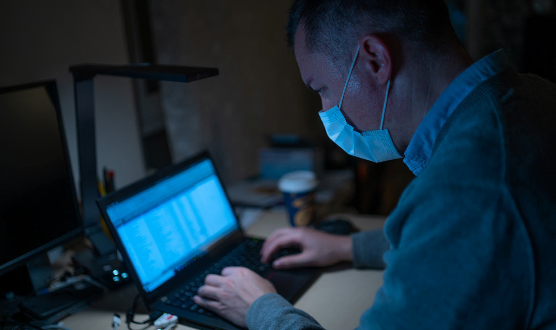 A pharmacy owner going over the financials of his business while wearing a face mask
