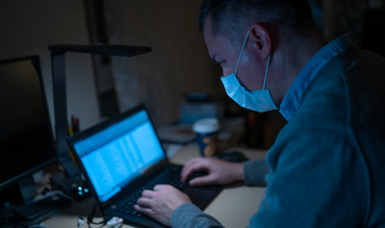 A pharmacy owner going over the financials of his business while wearing a face mask