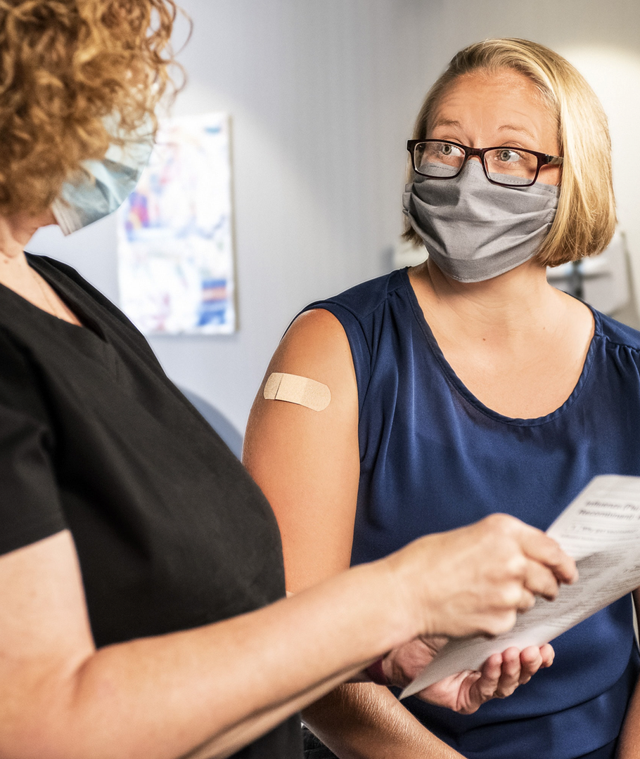 A pharmacist talking to a patient after administering a COVID-19 shot